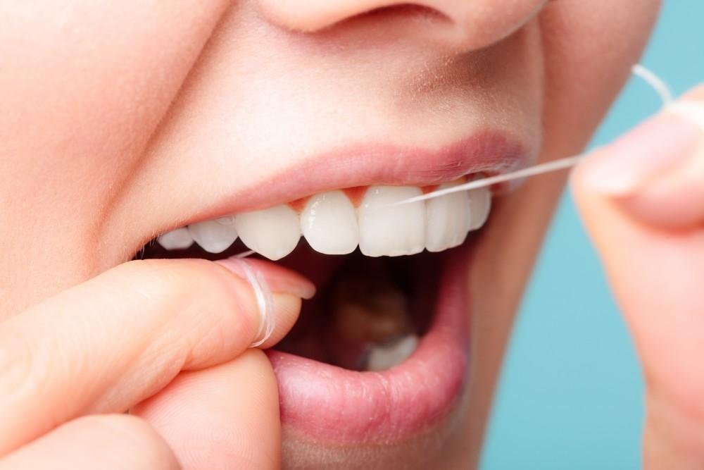 Close-up of floss threader being used under a dental bridge